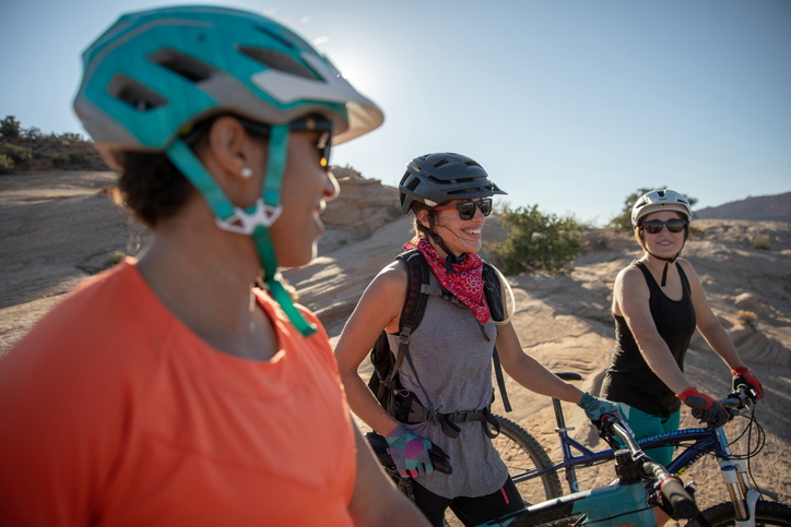 Three young women with bicycles in a desert area